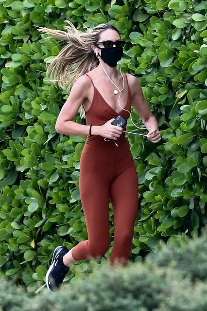 Supermodel Candice Swanepoel steps out to go for a run despite the falling rain in Miami today, November 11, 2020. The South African beauty wore a maroon bodysuit and mask for safety during her run along with a male friend. (Photo by Backgrid USA)