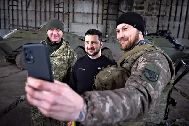 This handout picture taken and released by the Ukrainian Presidential press service on March 22, 2023 shows President Volodymyr Zelensky (C) taking a selfie with servicemen after meeting them in a warehouse and handing out awards, near Bakhmut. President Volodymyr Zelensky visited military positions near the frontline town of Bakhmut in eastern Ukraine, the scene of the longest and bloodiest battle since Russia's invasion, he said. (Photo by Handout/Ukrainian Presidential Press Service via AFP Photo)