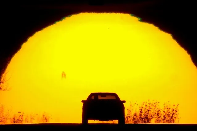 A motorist is silhouetted against the setting sun on the eve of the vernal equinox, Sunday, March 19, 2023, in Shawnee, Kan. The equinox marks the beginning of spring in the northern hemisphere with the day and night being roughly equal in duration. (Photo by Charlie Riedel/AP Photo)