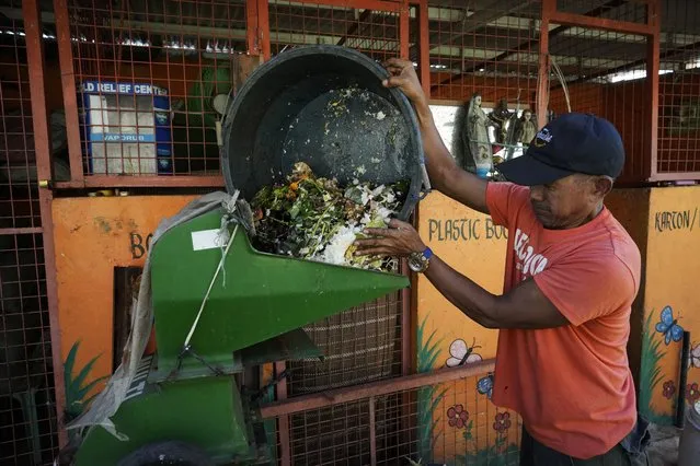 A worker pours garbage on a machine at a recycling facility in Malabon, Philippines on Monday February 13, 2023. Food waste emits methane as it breaks down and rots. Waste pickers are helping set up systems to segregate and collect organic waste, and establishing facilities to compost it. (Photo by Aaron Favila/AP Photo)