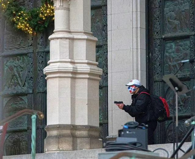 A man wearing a protective mask points his guns outside the Cathedral Church of St. John the Divine in the Manhattan borough of New York City, New York, U.S., December 13, 2020. (Photo by Jeenah Moon/Reuters)