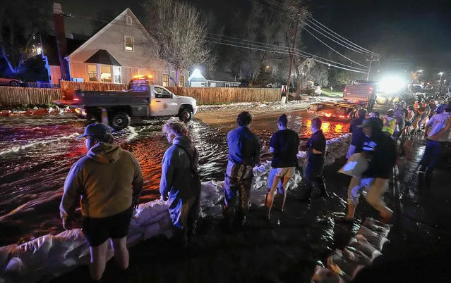 People work to protect homes into the night along 1700 South in Salt Lake City from the rising flow of Emigration Creek through Wasatch Hollow Park on Wednesday, April 12, 2023. As rapid snowmelt and possible April showers stoke fears of heavy flooding in the Northern Plains, state officials are announcing flood response plans, and residents are assembling thousands — if not hundreds of thousands – of sandbags to combat floods themselves. (Photo by Francisco Kjolseth/The Salt Lake Tribune via AP Photo)