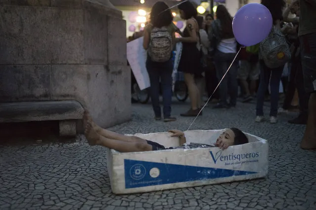 A boy plays with a foam box that is used to carry fish, during a demonstration against gender violence in Rio de Janeiro, Brazil, Tuesday, October 25, 2016. Women in Brazil organized protests condemning violence against women following the recent brutal gang rape of a woman on the outskirts of Rio de Janeiro by suspected drug dealers. The boy played with the box as his street vendor father sold water during the demonstration. (Photo by Leo Correa/AP Photo)