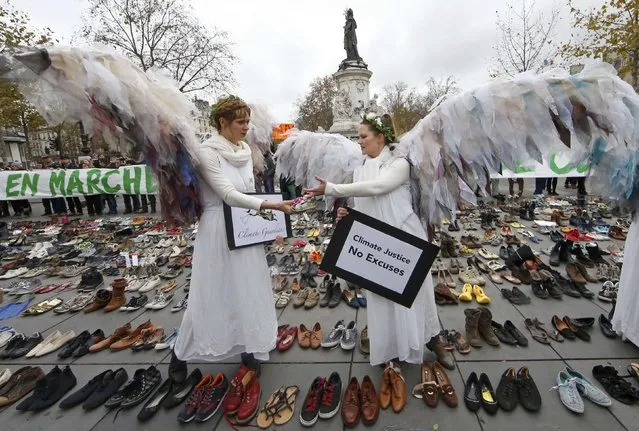 Environmental activists stand among pairs of shoes symbolically placed on the Place de la Republique, after the cancellation of a planned climate march following shootings in the French capital, ahead of the World Climate Change Conference 2015 (COP21), in Paris, France, November 29, 2015. (Photo by Eric Gaillard/Reuters)