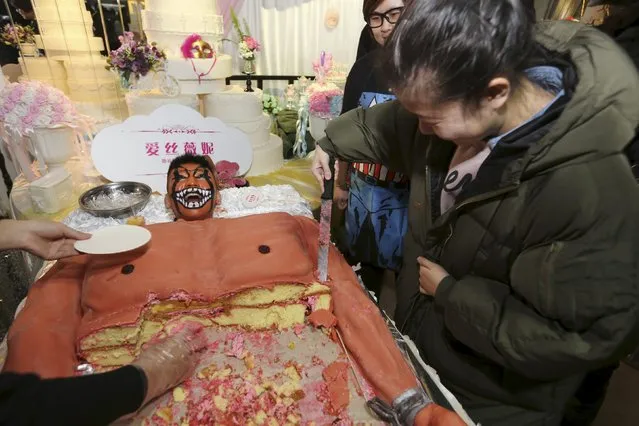 A staff member (top) pretends to scream in pain next to a cake, which was baked in the shape of a muscular man, for customers to try for free during a promotional event of a cake store in Shenyang, Liaoning province, China, December 6, 2015. (Photo by Reuters/Stringer)