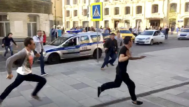 In this image taken from video provided by Viktoria Geranovich, a taxi driver, right, runs away from the scene after he crashed his taxi into pedestrians on a sidewalk near Red Square in Moscow, Russia, Saturday, June 16, 2018. Eight people, including two from Mexico, were injured in the crash. Video circulated on Russian social media and some news websites showed the taxi approaching a stopped line of cars, then veering onto the sidewalk and striking pedestrians. It then hit a traffic sign and bystanders tried to wrestle the driver out of the taxi, but he broke their grip and ran away; it was not clear how he was finally detained. (Photo by Viktoria Geranovich via AP Photo)