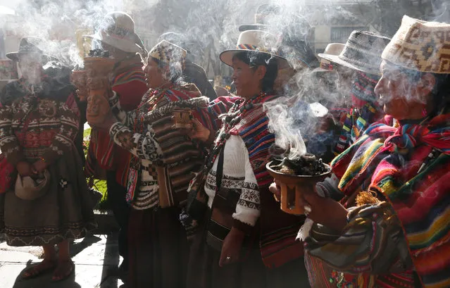 Andean religious leaders carry urns with burning incense in a procession of the Bolivian deity statuette “illa of Ekeko” as it is driven to the Alasitas Fair, in which Ekeko is the central figure, in La Paz, Bolivia, Saturday, January 24, 2015. (Photo by Juan Karita/AP Photo)