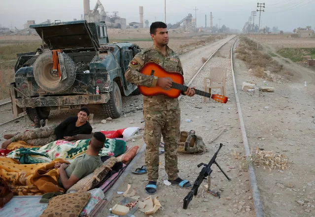 An Iraqi special forces policeman holds a guitar outside Karamah, south of Mosul, Iraq November 11, 2016. (Photo by Goran Tomasevic/Reuters)