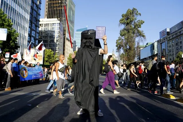 A student dressed as a character from the movie Star Wars holds up a representation of Chile's constitution during a protest against the government to demand universal free education and changes in the education system in Santiago, Chile, December 22, 2015. The words on the book read “Chile's Imperial Constitution”. (Photo by Ivan Alvarado/Reuters)