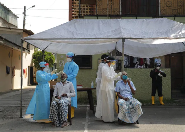 Sri Lankan municipal health workers take swab samples from residents to test for COVID-19 in Colombo, Sri Lanka, Wednesday, December 30, 2020. (Photo by Eranga Jayawardena/AP Photo)