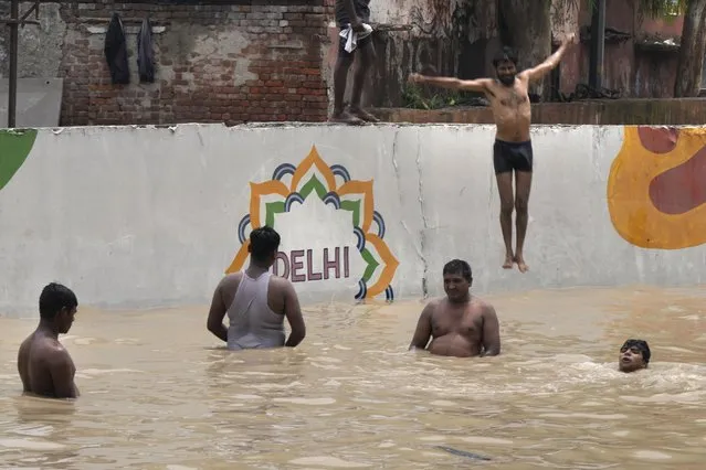 People living along the banks of the river Yamuna swim in the floodwaters at an underpass in New Delhi, India, Thursday, July 13, 2023. (Photo by Manish Swarup/AP Photo)