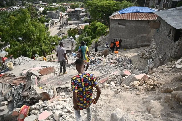People walk amongst damaged buildings in Jeremie, Haiti, after an earthquake hit western Haiti on June 6, 2023. (Photo by Richard Pierrin/AFP Photo)