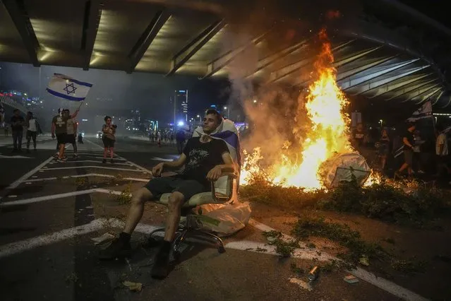 A bonfire burns as Israelis occupy the Ayalon Highway to protest against plans by Prime Minister Benjamin Netanyahu's government to overhaul the judicial system, in Tel Aviv, Thursday, July 20, 2023. (Phoot by Ariel Schalit/AP Photo)
