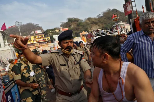A police officer asks a devotee to leave after he took a holy dip in the waters of river Ganges during Kumbh Mela, or the Pitcher Festival, in Haridwar, India, April 12, 2021. (Photo by Anushree Fadnavis/Reuters)