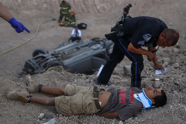 A policeman from the city of La Joya stands over an 18-year-old male who lies injured after crashing his vehicle while transporting two men and a woman who illegally crossed the U.S. border from Mexico in Penitas, Texas on August 31, 2018. (Photo by Adrees Latif/Reuters)