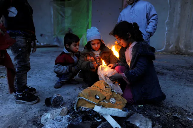 Syrians evacuated from eastern Aleppo, light a fire using plastic bags to keep warm, inside a shelter in government controlled Jibreen area in Aleppo, Syria November 30, 2016. (Photo by Omar Sanadiki/Reuters)