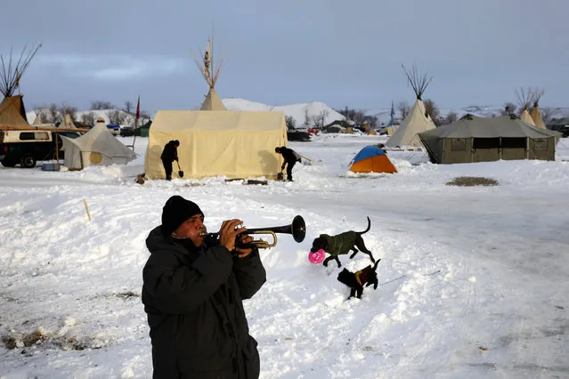 Tony Dujan plays the trumpet as the sun rises inside the Oceti Sakowin camp as “water protectors” continue to demonstrate against plans to pass the Dakota Access pipeline near the Standing Rock Indian Reservation, near Cannon Ball, North Dakota, U.S., December 3, 2016. (Photo by Lucas Jackson/Reuters)