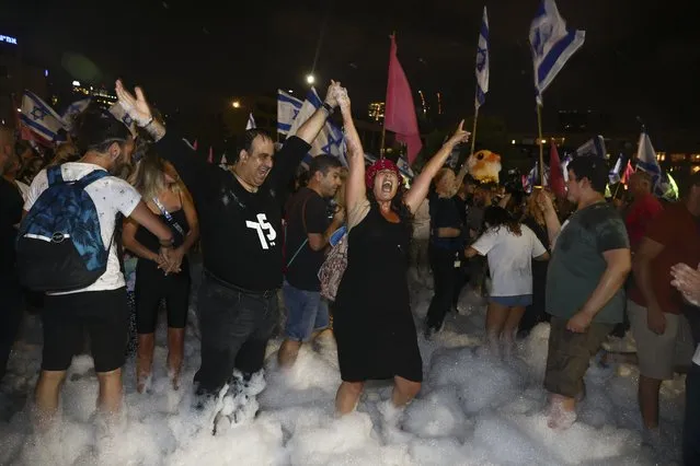 Israelis celebrate the swearing in of the new government in Tel Aviv, Israel, Sunday, June 13, 2021. Israel's parliament has voted in favor of a new coalition government, formally ending Prime Minister Benjamin Netanyahu's historic 12-year rule. Naftali Bennett, a former ally of Netanyahu became the new prime minister. (Photo by Oded Balilty/AP Photo)
