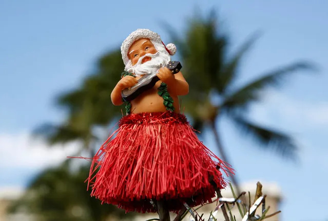 An ornament of Santa Claus in a hula skirt and playing a ukulele sits atop a Christmas tree on Waikiki Beach on Christmas Day in Honolulu, Hawaii, U.S. December 25, 2016. (Photo by Kevin Lamarque/Reuters)