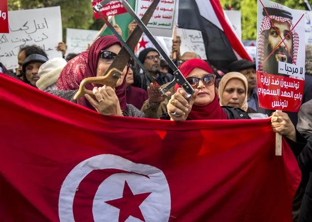 Tunisians demonstrate with saws, placards reading 'You are not welcomed' and showing Saudi Crown Prince Mohammed bin Salman, Tuesday November.27, 2018 in Tunis. Amid international concern about the killing of Saudi journalist Jamal Khashoggi, some 200 protesters gathered in central Tunis on Monday night to protest the prince's Tuesday arrival for talks with the Tunisian president. (Photo by Hassene Dridi/AP Photo)