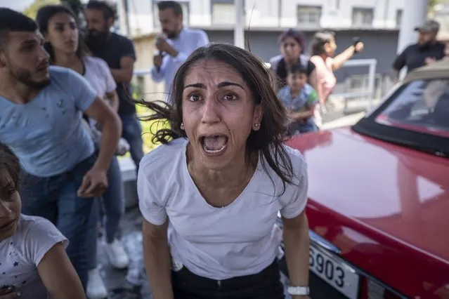A Syrian woman screams for help for her husband who was injured by stone throwing by members of the Lebanese Forces group, who attacked buses carrying Syrians traveling to vote in the town of Zouk Mosbeh, north of Beirut, Lebanon, Thursday, May 20, 2021. (Photo by Hassan Ammar/AP Photo)