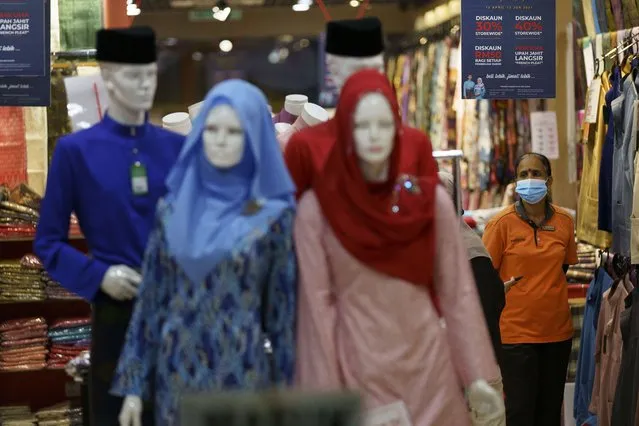 In this Saturday, April 24, 2021, photo, a clothing shop clerk wearing a protective mask waits for customers at the Ramadan bazaar in Kuala Lumpur, Malaysia. Malaysian Prime Minister Muhyiddin Yassin announced Monday that the whole country will be placed under a near lockdown for about a month but all economic sectors will be allowed to operate. (Photo by Vincent Thian/AP Photo)