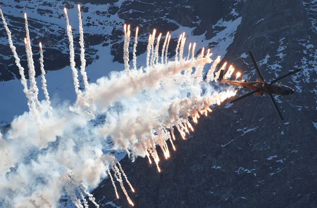 A Swiss Air Force Super Puma Cougar helicopter releases flares during a flight demonstration over the Axalp in the Bernese Oberland, Switzerland on October 10, 2018. (Photo by Arnd Wiegmann/Reuters)