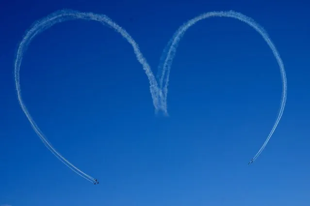Brazil's aerial demonstration Smoke Squadron creates the shape of a heart in the sky over the Planalto presidential palace during the arrival of the reliquary containing the heart of Brazil's former emperor Dom Pedro I in Brasilia, Brazil, Tuesday, August 23, 2022. The heart arrived from Portugal for display for celebrations of Brazil's independence bicentennial on Sept. 7. (Photo by Eraldo Peres/AP Photo)