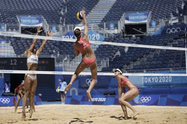 Anouk Verge-Depre, top right, of Switzerland, takes a shot as teammate Joana Heidrich, right, watches while Tina Graudina, of Latvia, defends during a women's beach volleyball Bronze match at the 2020 Summer Olympics, Friday, August 6, 2021, in Tokyo, Japan. (Photo by Petros Giannakouris/AP Photo)