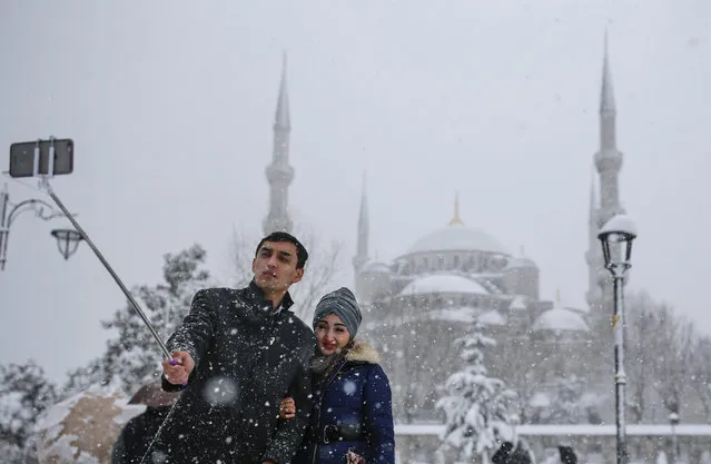 In this photo taken on Monday, January 9, 2017, a couple takes a selfie at Sultanahmet district, one of Istanbul's main tourist attractions. These days, with a string of terror attacks targeting Istanbul still fresh in his memory, some residents say they are adapting their daily routines because of fears they could become the latest victims of violent extremism. (Photo by Emrah Gurel/AP Photo)