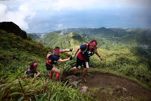 The three competitors of “Les +Jolies+ Genes” take part in a trail race on the Montagne Pelee on the French Caribbean island of Martinique, on December 8, 2023, as part of the “Raid des Alizes”, an exclusively all-female multi sport competition. Each team represents a charity project of their choice during the competition. Depending on the final ranking, donations go directly to the charities represented. (Photo by Anne-Christine Poujoulat/AFP Photo)