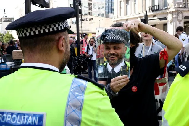 A demonstrator holds a mirror in front of a police officer during an Extinction Rebellion climate activists' protest, at Oxford Circus, in London, Britain on August 25, 2021. (Photo by Henry Nicholls/Reuters)