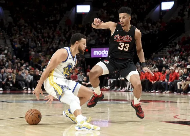 Golden State Warriors guard Stephen Curry, left, dribbles the ball on Portland Trail Blazers forward Toumani Camara, right, during the second half of an NBA basketball game in Portland, Ore., Sunday, December 17, 2023. The Warriors won 118-114. (Photo by Steve Dykes/AP Photo)