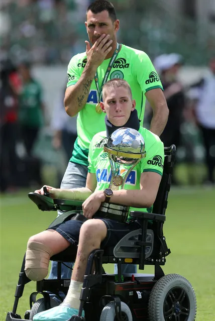 Brazilian Chapecoense goalkeeper Jackson Follmann (C), a survivor of the LaMia airplane crash in Colombia, receives the Copa Sudamericana trophy in Arena Conda stadium before a charity match between Chapecoense and Palmeiras in Chapeco, Brazil on January 21, 2017. (Photo by Paulo Whitaker/Reuters)