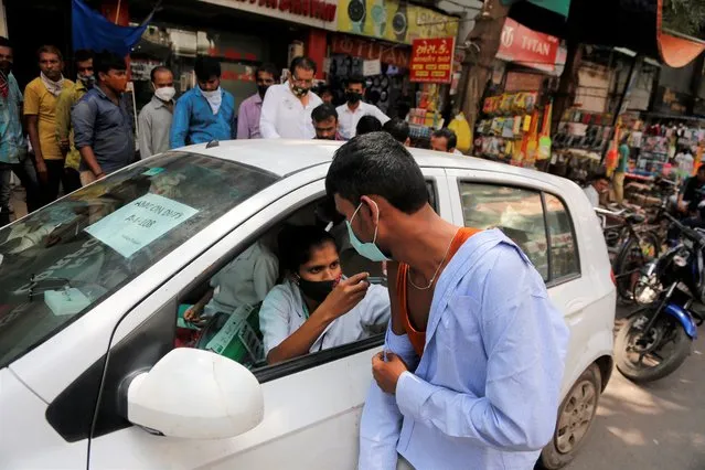 A health worker administers the vaccine for COVID-19 during a vaccination drive at a market place in Ahmedabad, India, Friday, September 24, 2021. (Photo by Ajit Solanki/AP Photo)