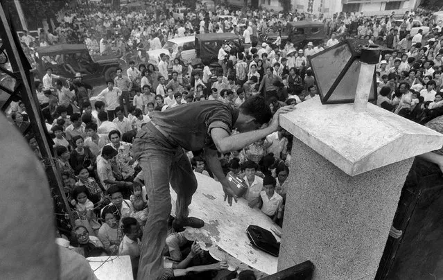 In this April 29, 1975, file photo, South Vietnamese civilians try to scale the 14-foot wall of the U.S. embassy in Saigon, trying to reach evacuation helicopters as the last Americans departed from Vietnam. More than two bitter decades of war in Vietnam ended with the last days of April 1975. Today, 40 years later, former Associated Press correspondent Peter Arnett has written a new memoir, “Saigon Has Fallen”, detailing his experience covering the war for The AP. (Photo by AP Photo)