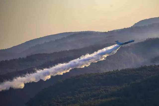 An aircraft drops water at a wildfire as it participates in a wildfire extinguishing operation, southern Turkey, Sunday, August 8, 2021. Wildfires in Turkey, described as Turkey's worst in living memory, started on July 28 amid a ferocious heat wave and raged on for days across more than half of Turkey's provinces. (Photo by Emre Tazegul/AP Photo)