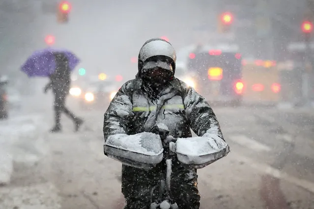 A delivery worker rides a bicycle on East 125th Street in heavy snowfall during winter weather in Manhattan in New York City, U.S., February 13, 2024. (Photo by Mike Segar/Reuters)