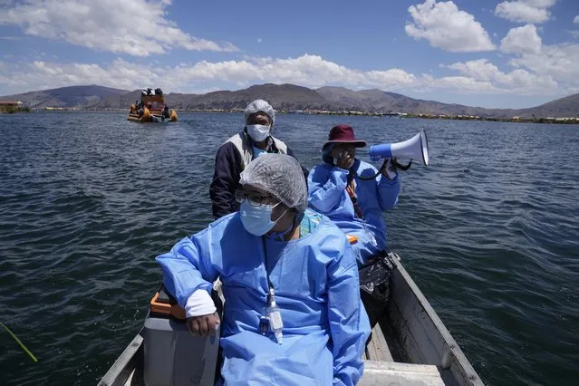 Healthcare workers travel on a boat with coolers containing doses of the Pfizer COVID-19 vaccine as part of a a door-to-door vaccination campaign aimed at Lake Titicaca residents, in Puno, Peru, Wednesday, October 27, 2021. (Photo by Martin Mejia/AP Photo)