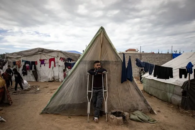 An injured Palestinian man stands outside his tent in the Rafah camp, southern Gaza Strip, 18 February 2024. Since 07 October 2023, up to 1.9 million people, or more than 85 percent of the population, have been displaced throughout the Gaza Strip, some more than once, according to the United Nations Relief and Works Agency for Palestine Refugees in the Near East (UNRWA), which added that most civilians in Gaza are in “desperate need of humanitarian assistance and protection”. (Photo by Haitham Imad/EPA)