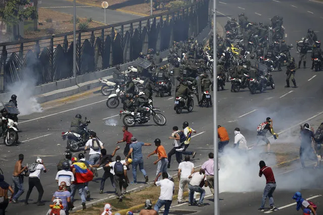 Opponents to Venezuela's President Nicolas Maduro confront loyalist Bolivarian National Guard troops firing tear gas at them, outside La Carlota military airbase in Caracas, Venezuela, Tuesday, April 30, 2019. Venezuelan opposition leader Juan Guaidó took to the streets with activist Leopoldo Lopez and a small contingent of heavily armed troops early Tuesday in a bold and risky call for the military to rise up and oust socialist leader Nicolas Maduro. (Photo by Fernando Llano/AP Photo)