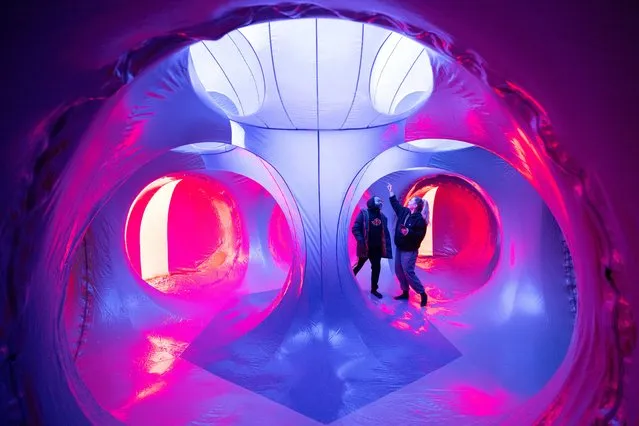 People inspect the interior of Architects of Air's latest Luminaria creation, entitled Lumini, during its inaugural test inflation in Nottingham, central England, on March 5, 2024. Taking inspiration from Islamic architecture, Archimedean solids and Gothic cathedrals, Architects of Air have created a series of structures that form a maze of winding paths and domes that members of the public are able to experience as an immersive display of iridescent shapes and colours. The Luminarium, designed by company founder Alan Parkinson, in various formats has been presented all over the world for the past 32 years and is now due to be showcased to the public in Spring 2024. (Photo by Oli Scarff/AFP Photo)