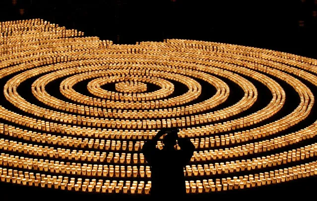 A staff wearing a protective mask, amid the coronavirus disease (COVID-19) outbreak, takes picture of 6,500 candle lights as he prepares for a ceremony to wish for overcoming the pandemic and good luck in the upcoming New Year at Hasedera Buddhist temple in Kamakura, south of Tokyo, Japan, December 31, 2021. (Photo by Kim Kyung-Hoon/Reuters)