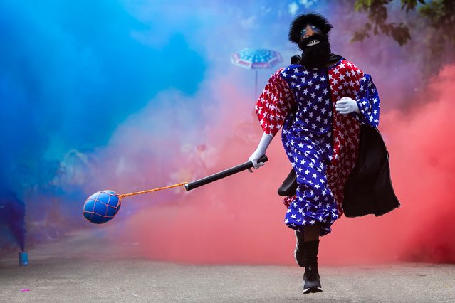 A member of a traditional “Bate-Bola” group, an annual cultural festivity which takes place during the carnival period, celebrates at the street in a suburb in Rio de Janeiro, Brazil, on February 14, 2021. Rio’s city government officially suspended the annual world famous Carnival and its associated street parties due to the COVID-19 pandemic but many traditional parties still took place illegally in defiance of the measures. (Photo by Carl De Souza/AFP Photo)