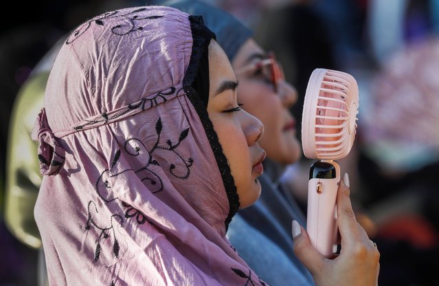 A Muslim woman uses a portable fan after morning prayers to mark Eid al-Fitr at a park in Quezon City, Metro Manila, Philippines, 10 April 2024. Muslims worldwide celebrate Eid al-Fitr, a two or three-day festival at the end of the Muslim holy fasting month of Ramadan.It is one of the two major holidays in Islam. During Eid al-Fitr, Most People travel to visit each other in town or outside of it and children receive new clothes and money to spend for the occasion. (Photo by Rolex dela Peña/EPA/EFE)
