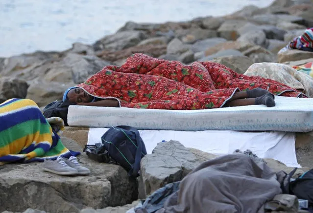 Migrants sleep on the rocky beach at the Franco-Italian border near Menton, southeastern France Wednesday, June 17, 2015. European Union nations failed to bridge differences Tuesday over an emergency plan to share the burden of the thousands of refugees crossing the Mediterranean Sea, while on the French-Italian border, police in riot gear forcibly removed dozens of migrants. (AP Photo/Lionel Cironneau)