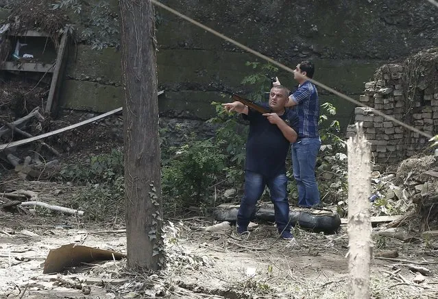 Armed municipality workers search for a white tiger that escaped when floods destroyed its enclosure, in Tbilisi, Georgia, June 17, 2015. Tigers, lions, bears and wolves were among more than 30 animals that escaped from a Georgian zoo and onto the streets of the capital Tbilisi on Sunday during floods that killed at least 12 people. REUTERS/David Mdzinarishvili