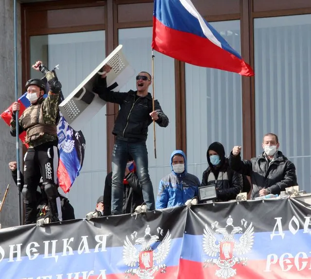 Pro-Russian activists who seized the main administration building in the eastern Ukrainian city of Donetsk deploy a flag of the so-called Donetsk Republic and hold a Russian flag on April 7, 2014, in Donetsk. They proclaimed on April 7 the creation of a sovereign “people's republic” independent of Kiev's rule. (Photo by Alexander Khudoteply/AFP Photo)