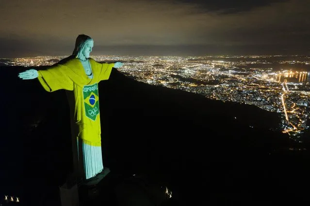 The colors of the Brazilian Olympic team are projected on the statue of Christ the Redeemer by the Brazilian Olympic Committee as a reminder of how sport can inspire in the fight against COVID-19, one hundred days before the Tokyo Olympic Games, in Rio de Janeiro, Brazil, Wednesday, April 14, 2021. (Photo by Lucas Dumphreys/AP Photo)
