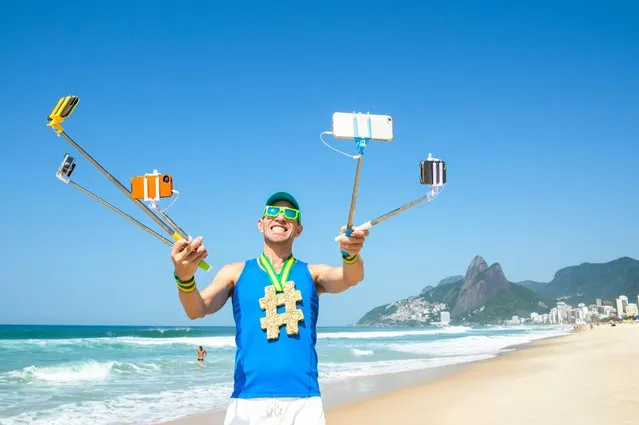 Hashtag gold medal athlete posing for a picture with mobile phones on selfie sticks on Ipanema Beach in Rio de Janeiro, Brazil. (Photo by Lazyllama/Alamy Stock Photo)